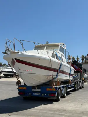 Θαλαμηγός σκάφος φορτωμένο και δεμένο σε χαμηλή πλατφόρμα μεταφοράς στο λιμάνι