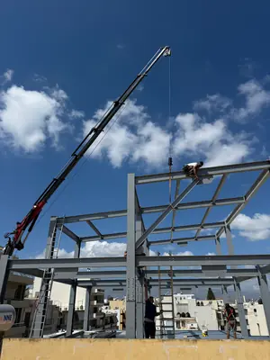 Ανύψωση μεταλλικής δοκού με γερανό πάνω από μεταλλικό σκελετό κτηρίου υπό κατασκευή