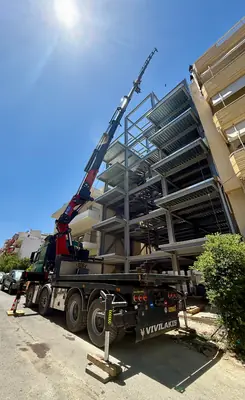 Γερανοφόρο όχημα σε εργοτάξιο δίπλα σε μεταλλικό σκελετό πολυώροφου κτηρίου